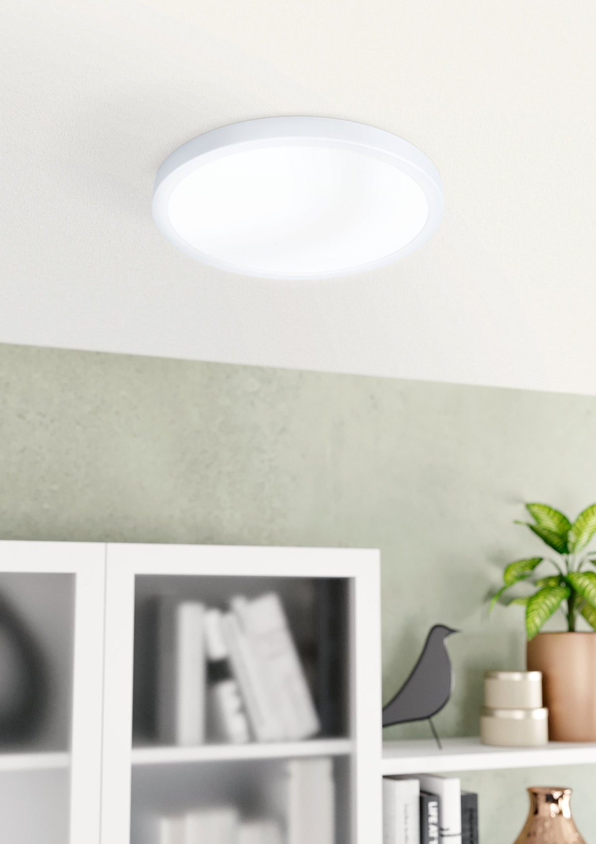 Luminaire allumé fixé au plafond au-dessus d'une bibliothèque blanche, ambiance salon clair