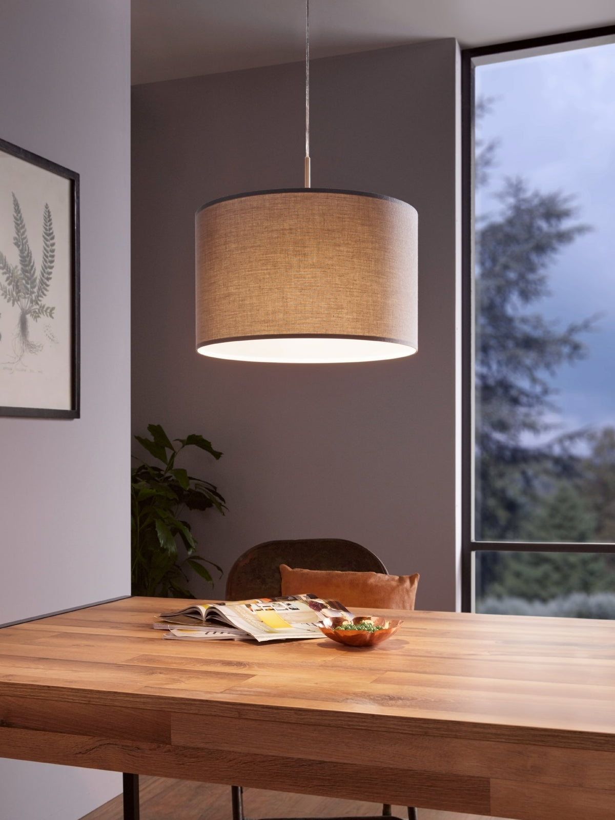 Mise en ambiance au-dessus d'une table en bois, suspension allumée dans salle à manger.