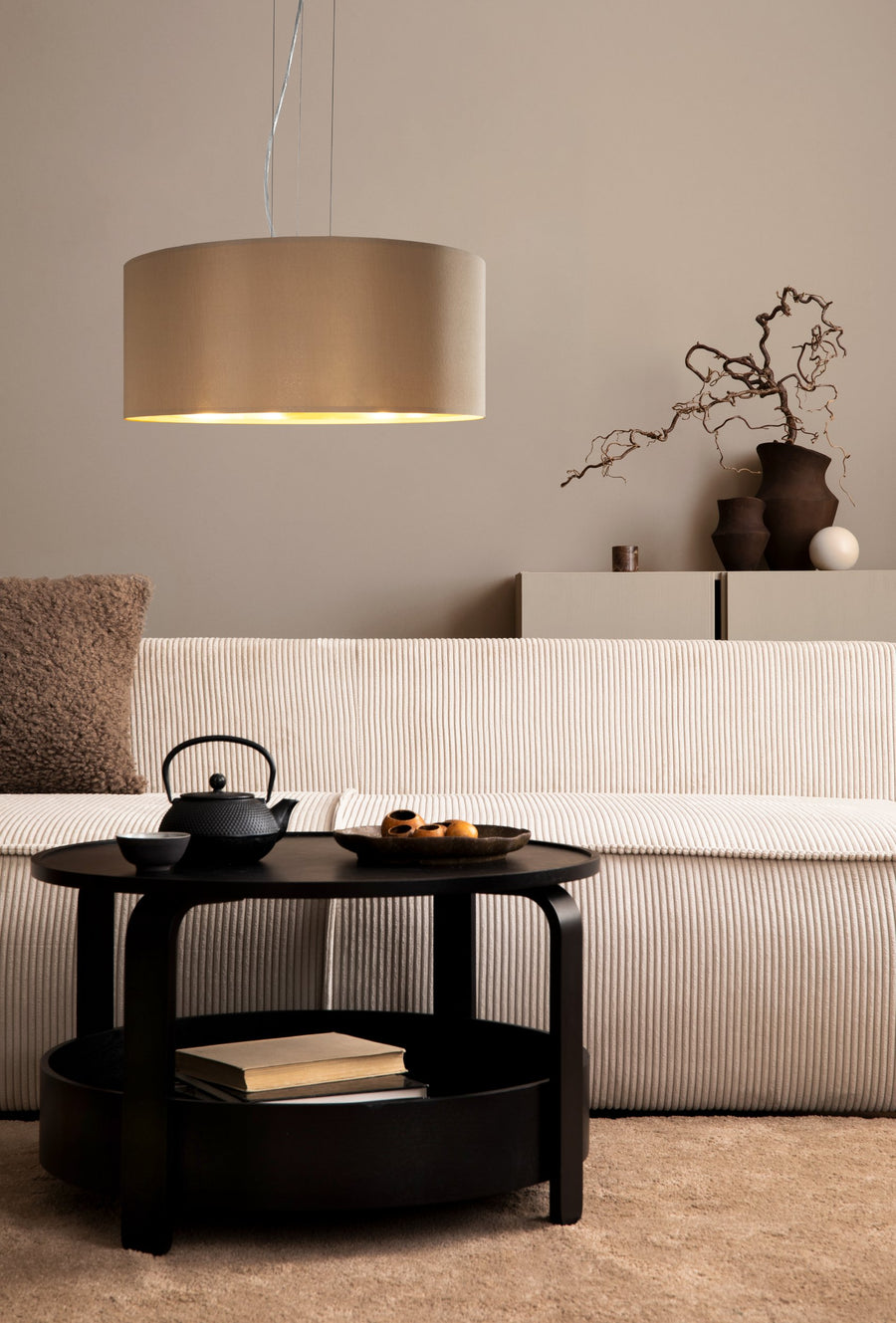 Mise en scène dans un salon beige avec canapé, table basse et théière noire.