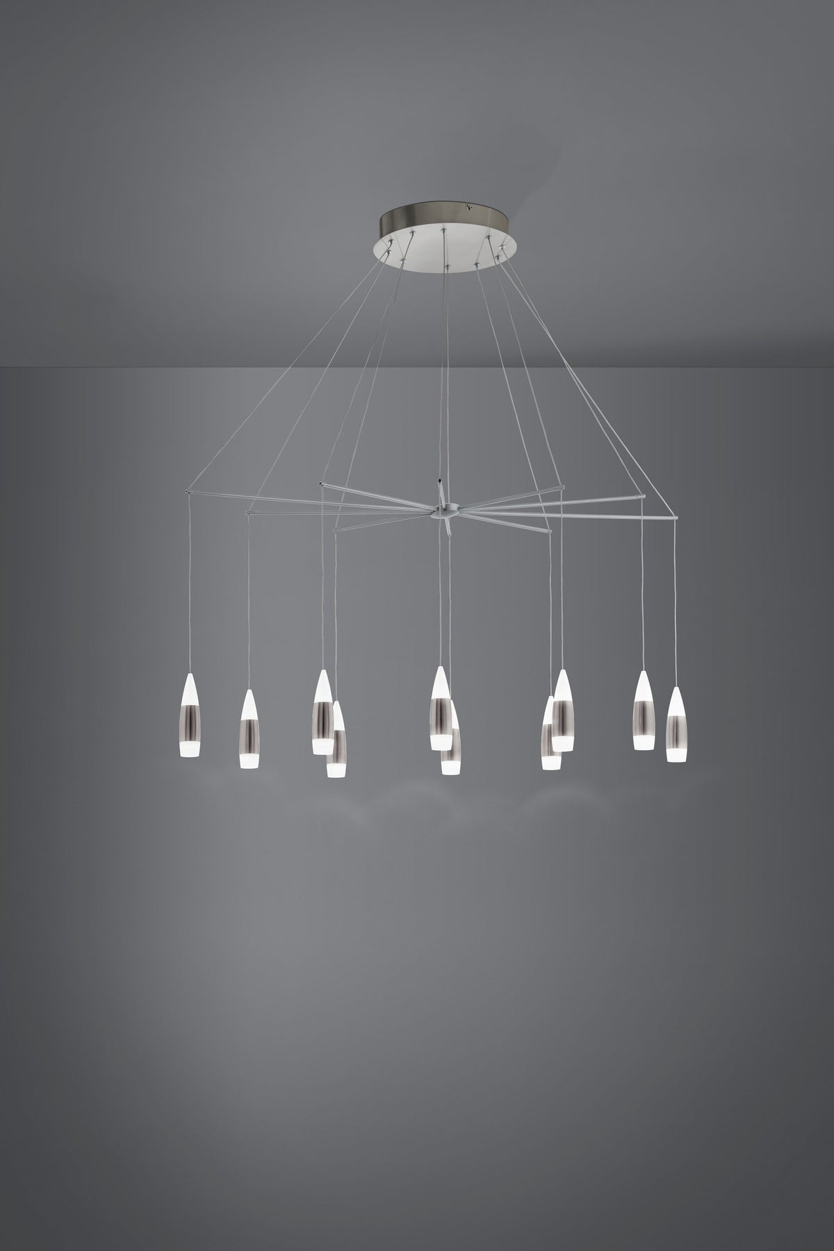 Mise en ambiance sombre montrant la suspension allumée, ses câbles et diffuseurs blancs suspendus