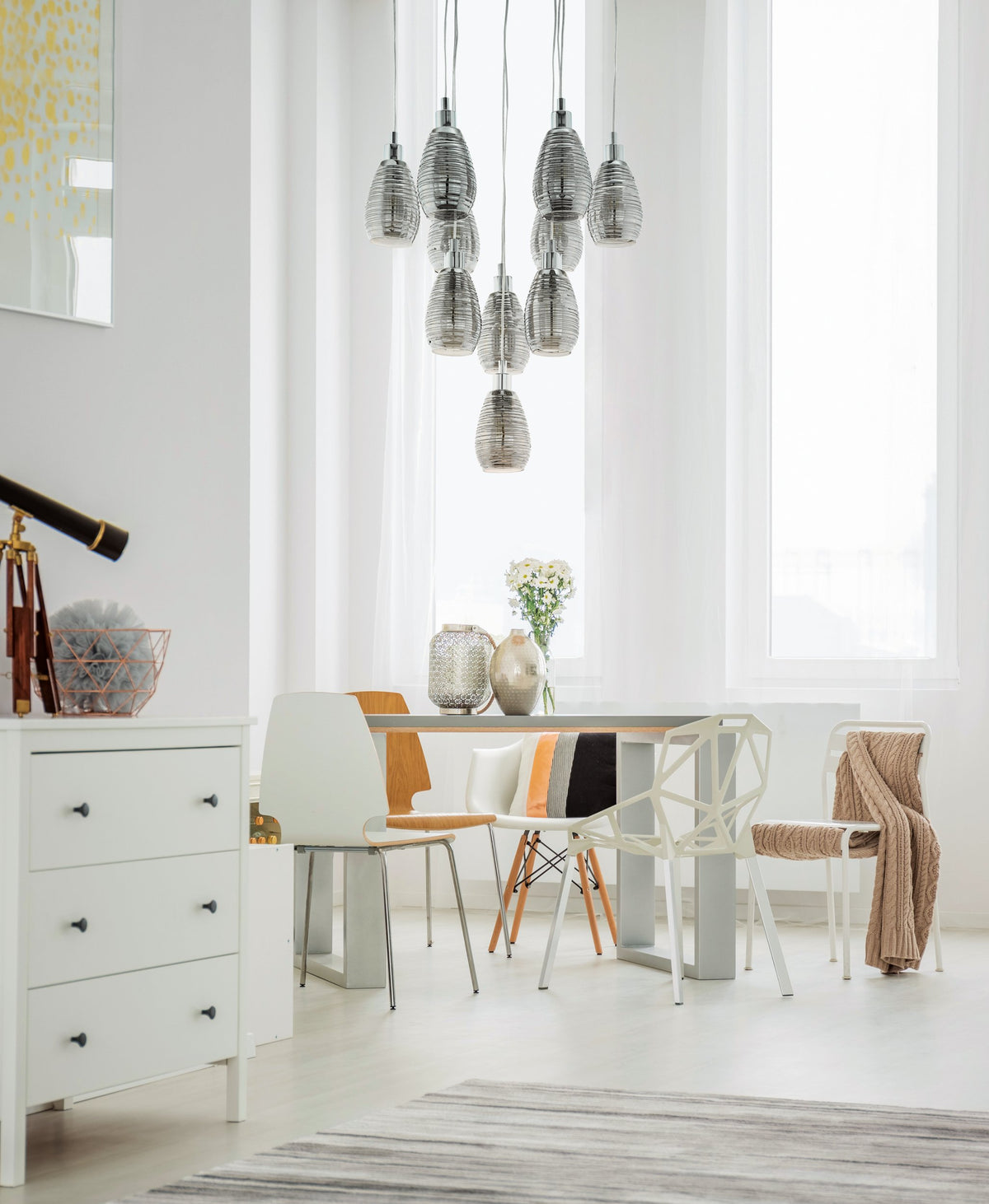 Mise en ambiance : la suspension éclaire une salle à manger blanche avec table et chaises design.