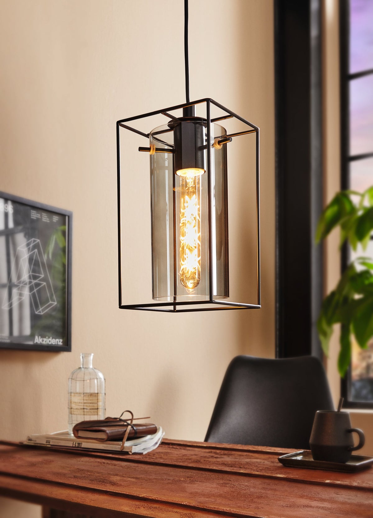 Mise en ambiance du luminaire suspendu au-dessus d'une table en bois avec livres et plante