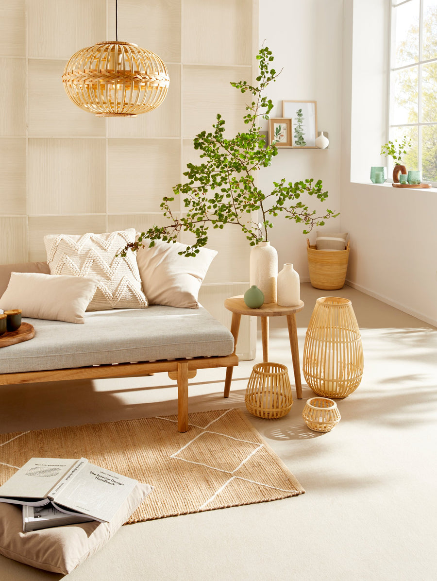 Ambiance lumineuse avec la suspension en rotin au-dessus d'un canapé et de plantes.