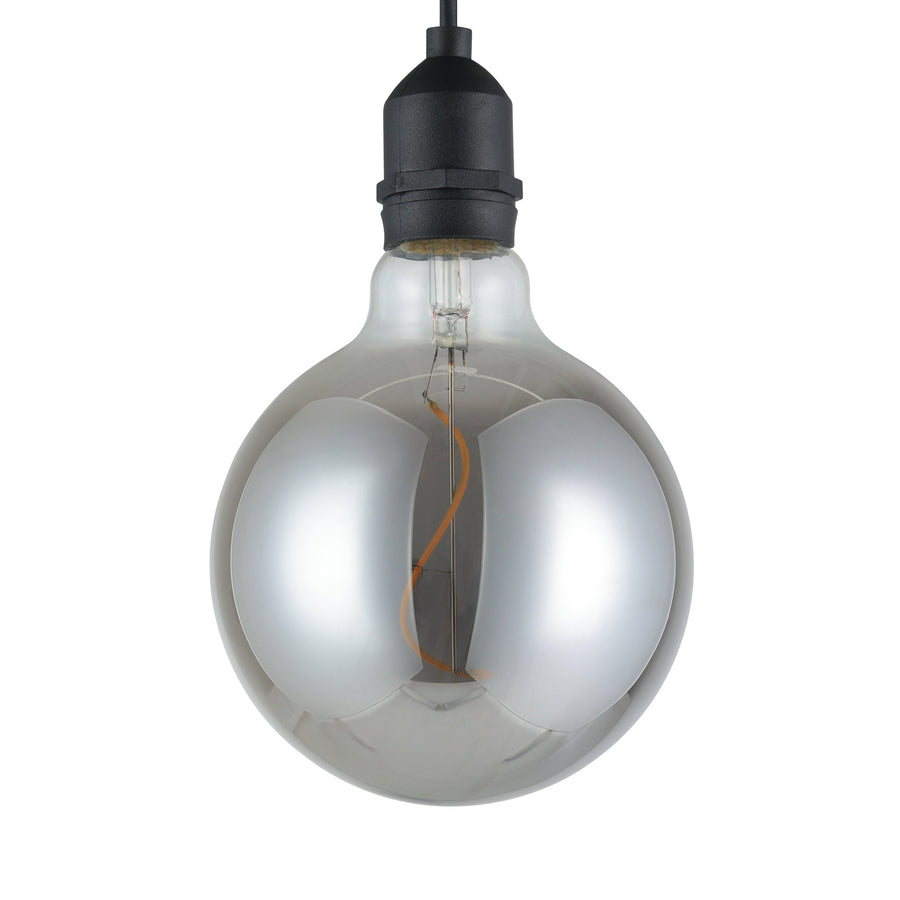 Gros plan sur l'ampoule transparente, filament sinueux et douille noire, fond blanc.