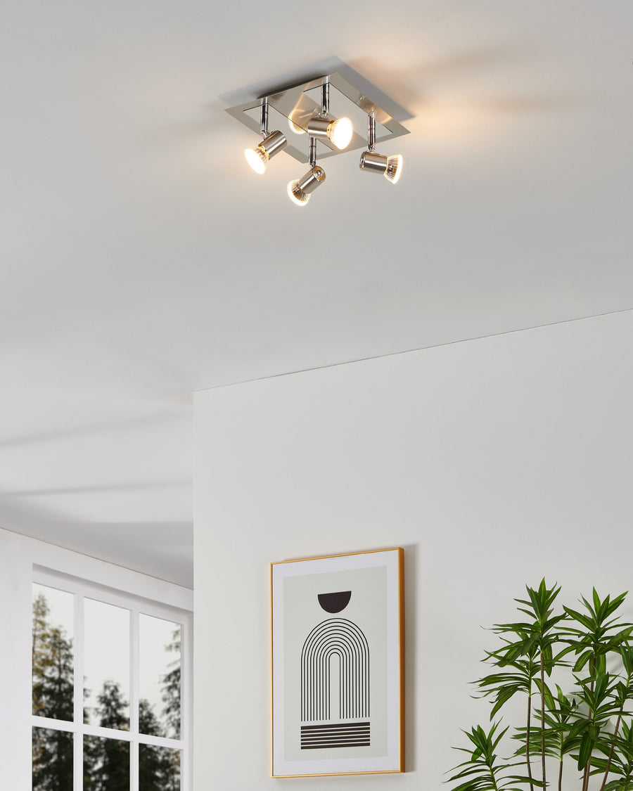 Spot installé au plafond dans un salon moderne, éclairant une pièce blanche avec cadre et plante.