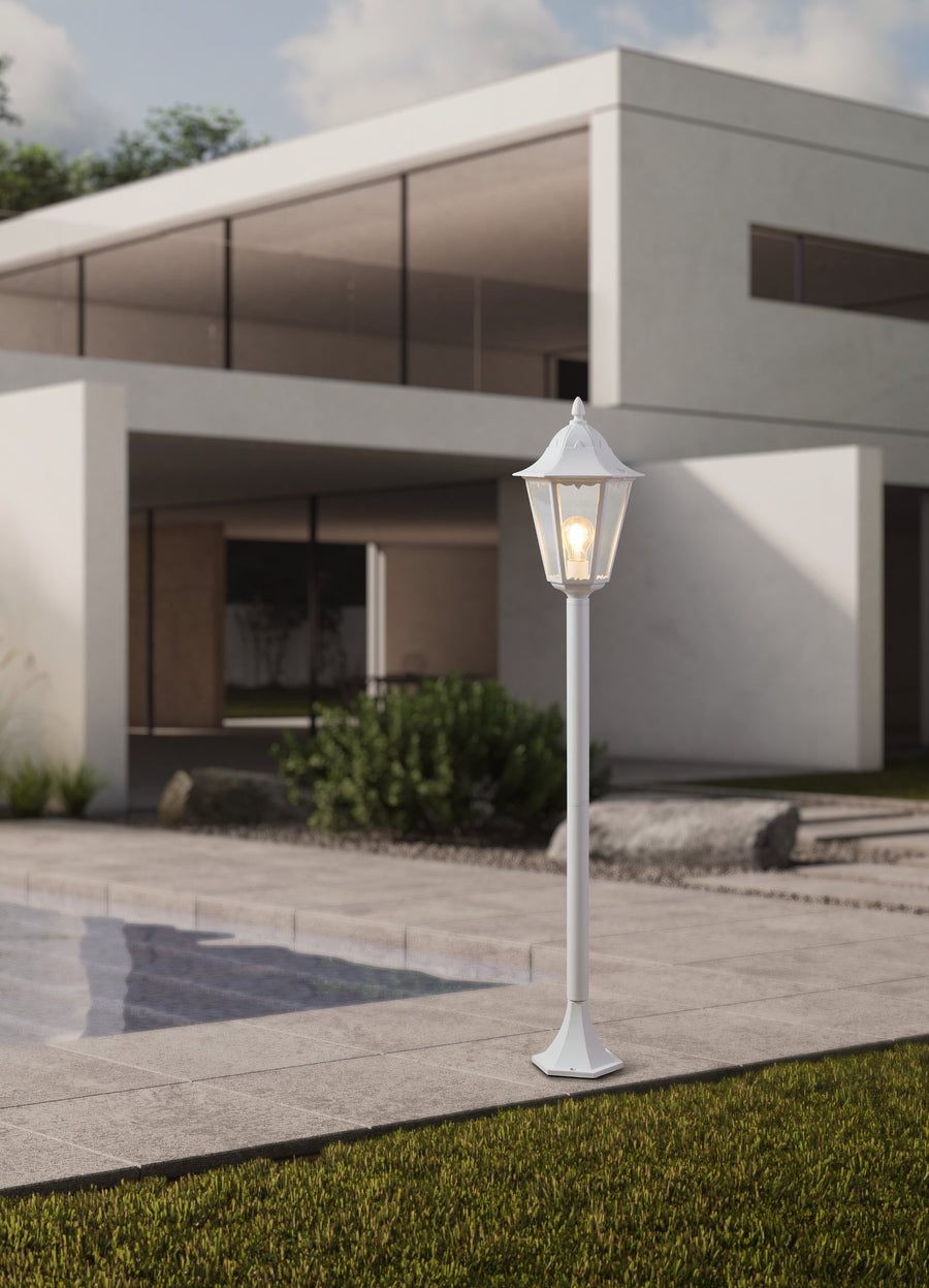 Mise en situation du lampadaire éclairé devant une maison moderne avec terrasse et gazon.