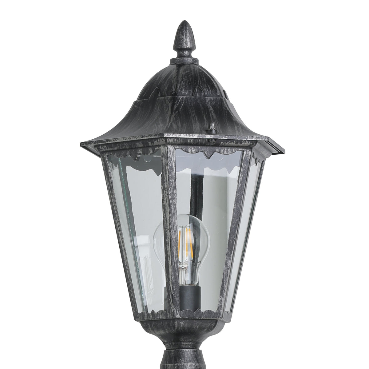 Gros plan sur la lanterne : verre transparent, ampoule filament, finition métal noir vieilli.