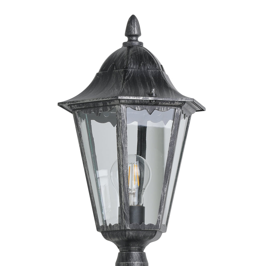 Gros plan sur la lanterne : verre transparent, ampoule filament, finition métal noir vieilli.