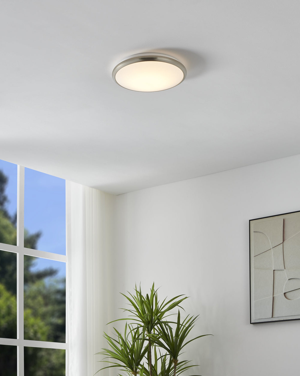 Mise en ambiance du luminaire allumé au plafond d'un salon clair avec plante