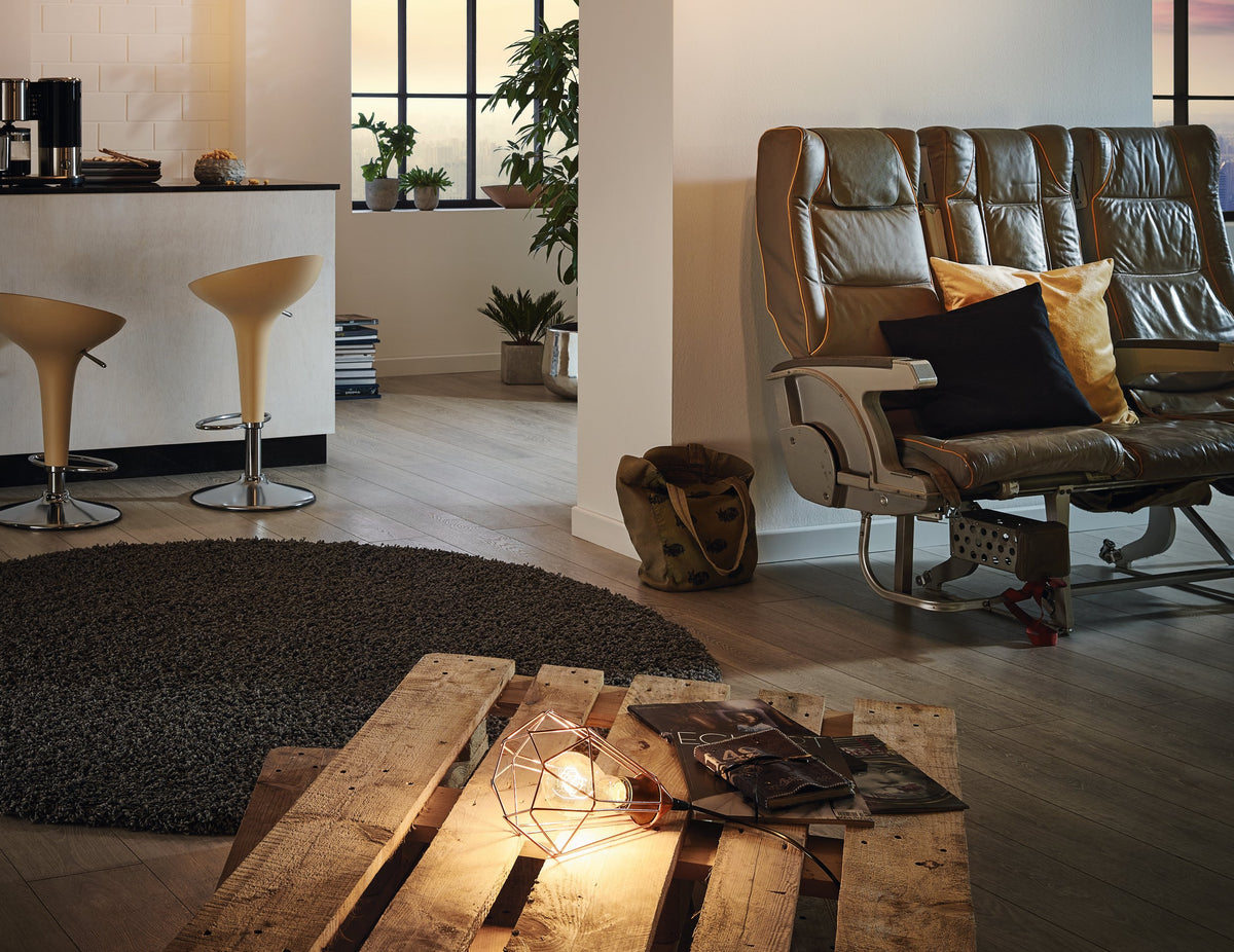 Mise en ambiance : lampe posée sur une table basse en palettes, salon chaleureux.