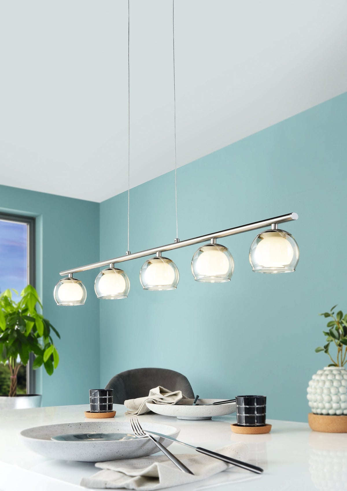 Mise en ambiance au-dessus d'une table de salle à manger, mur turquoise et plantes vertes