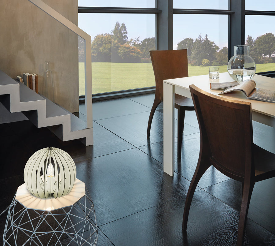 Lampe allumée posée sur une table basse dans un intérieur ouvert sur le jardin