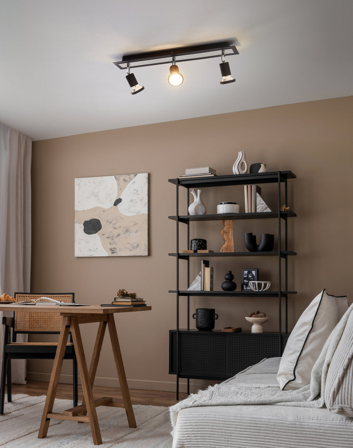 Mise en ambiance dans un salon beige avec bibliothèque noire et canapé