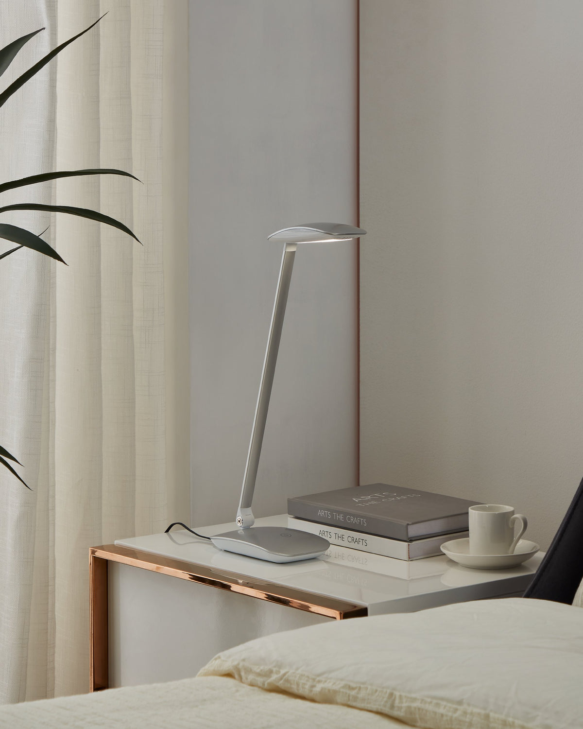 Lampe posée sur une table de nuit, près de livres, d'une tasse et d'un lit