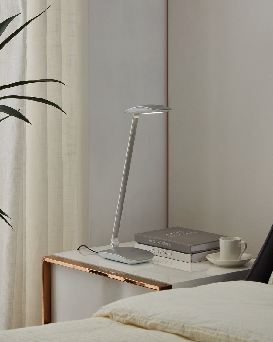 Lampe posée sur une table de nuit, près de livres, d'une tasse et d'un lit