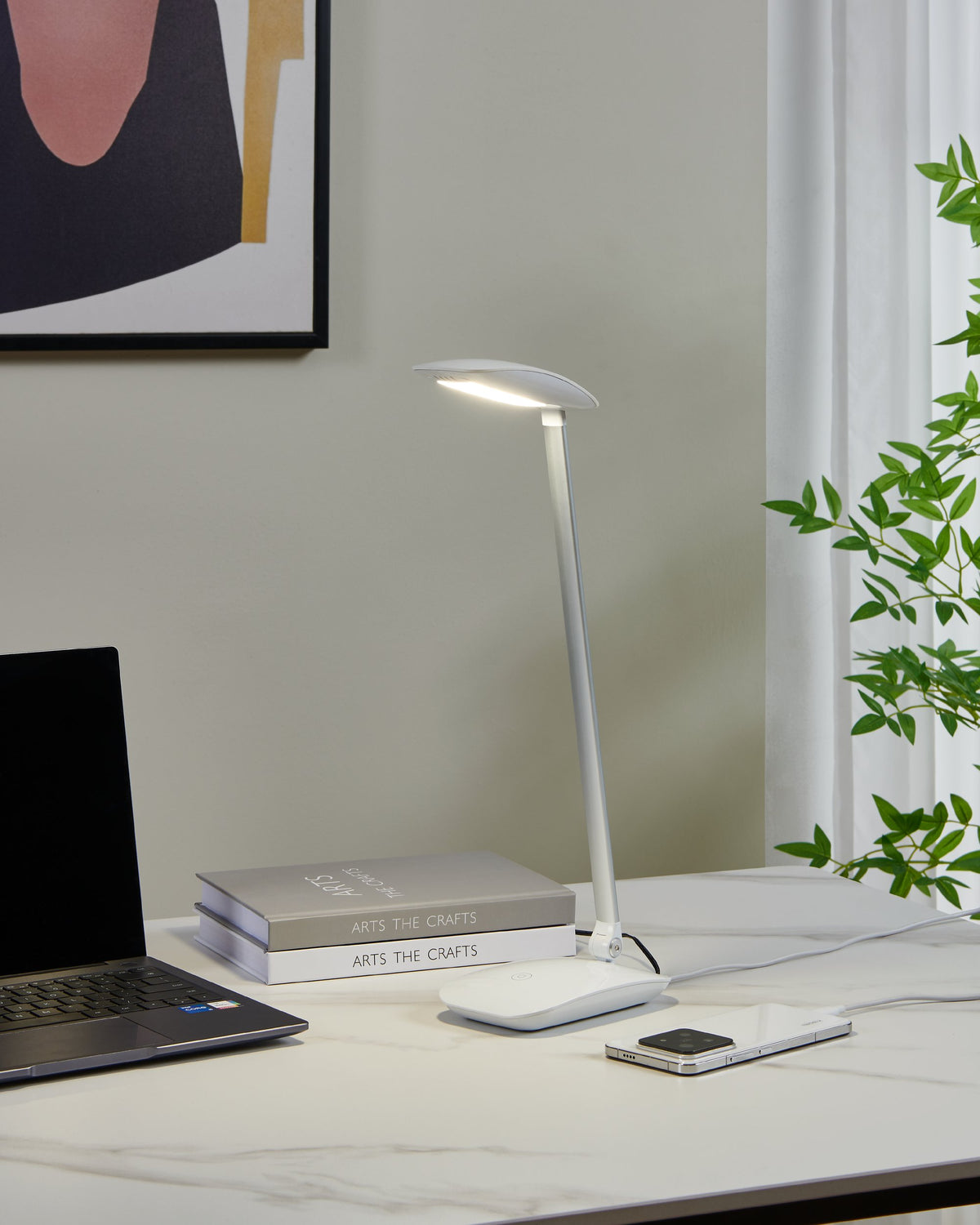 Mise en ambiance sur un bureau en marbre, lampe allumée près d'un ordinateur portable