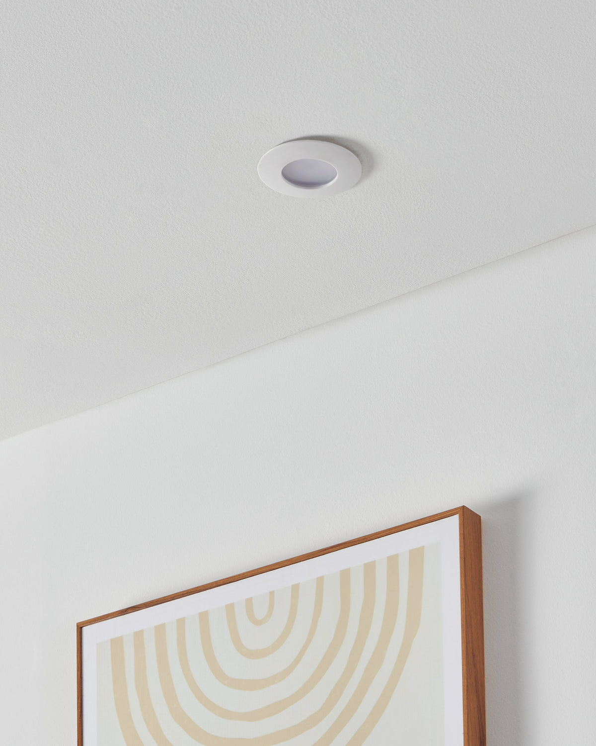 Spot encastré dans un plafond blanc, installé au-dessus d'un cadre en bois