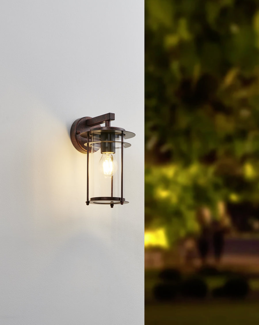 Applique murale éclairée le soir, halo lumineux sur mur et jardin flou