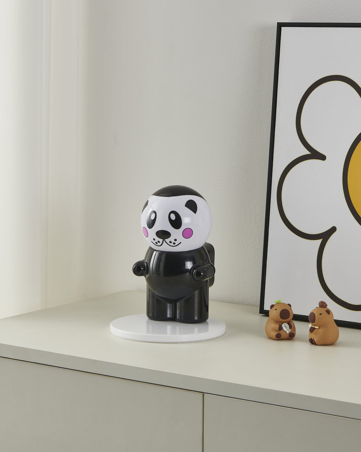 Lampe panda éteinte posée sur un meuble blanc près d'un cadre et de figurines
