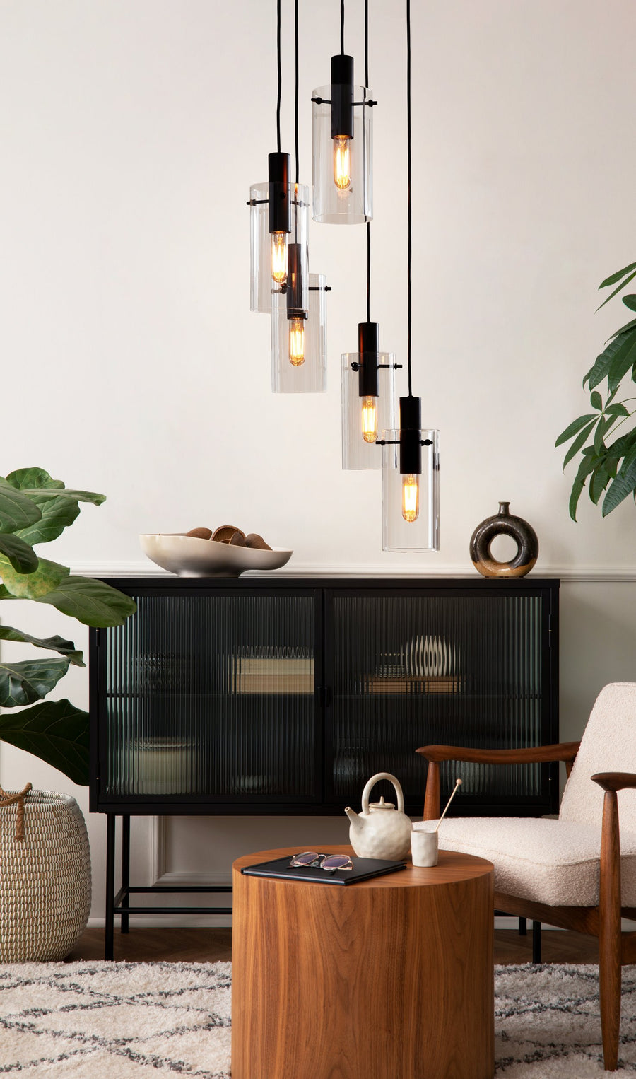 Ambiance intérieure avec buffet noir vitré, fauteuil et suspensions en verre allumées