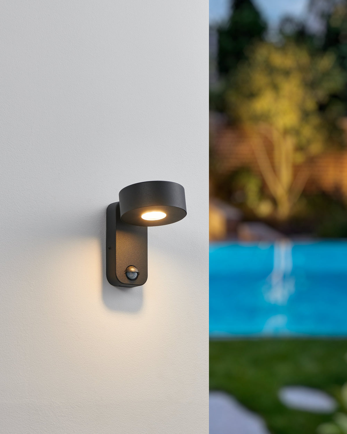 Mise en ambiance nocturne, applique allumée éclairant un mur près d'une piscine
