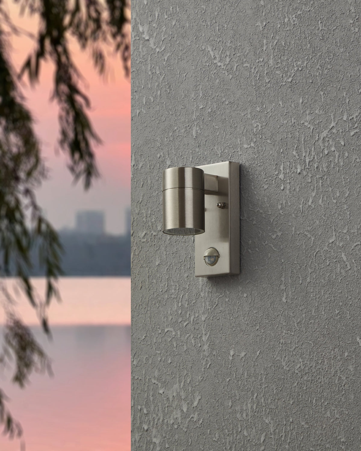 Vue de face de l'applique éteinte fixée sur une façade grise, détecteur inclus.