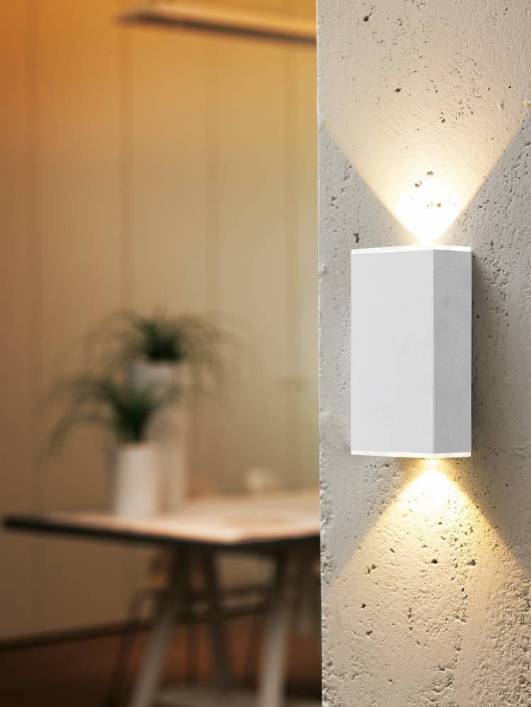 Applique blanche fixée sur un mur en béton, éclairant vers le haut et le bas