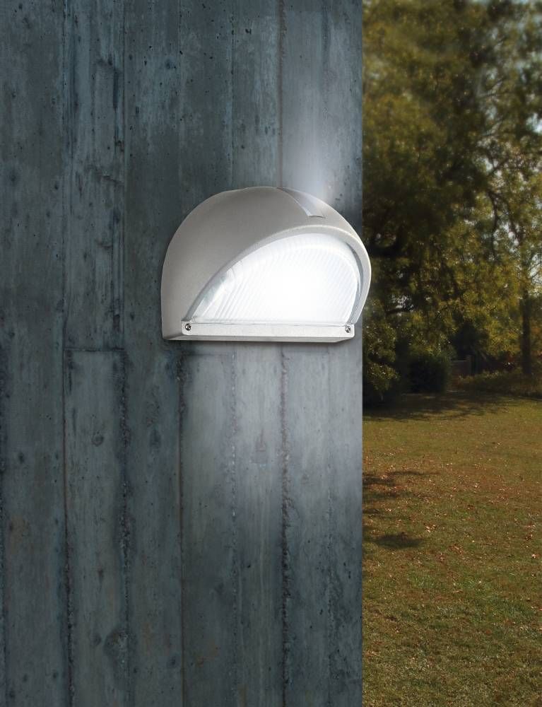 Applique blanche installée sur un pilier en béton devant un jardin arboré