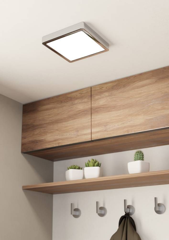 Mise en ambiance dans une entrée, plafonnier allumé au-dessus d'un meuble en bois