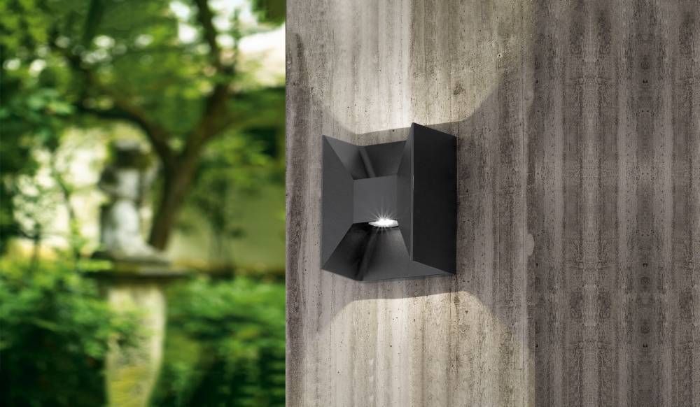 Applique murale anthracite installée sur mur béton, éclairant un jardin arboré