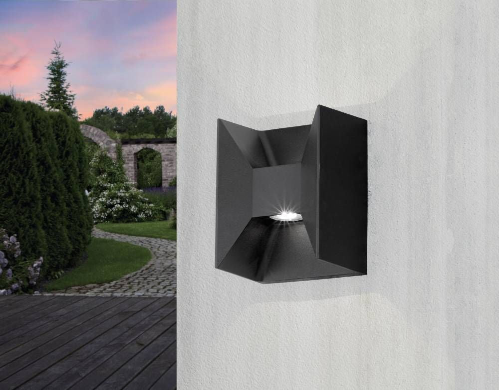 Luminaire extérieur fixé sur mur blanc clair, jardin paysager et ciel rosé