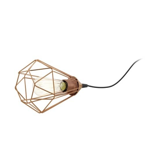 Lampe à poser couchée sur fond blanc, cage géométrique cuivrée et ampoule à filament visible.
