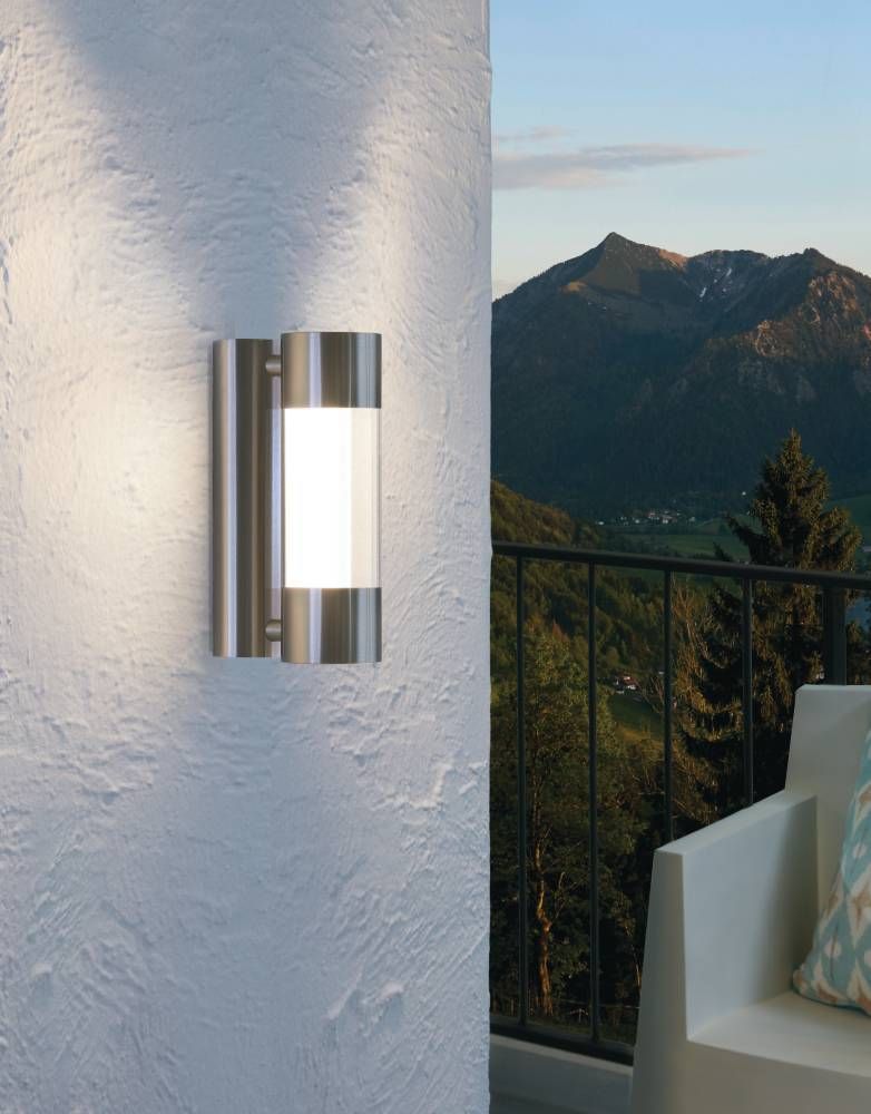 Applique extérieure allumée sur mur blanc, avec vue sur montagnes et balcon.