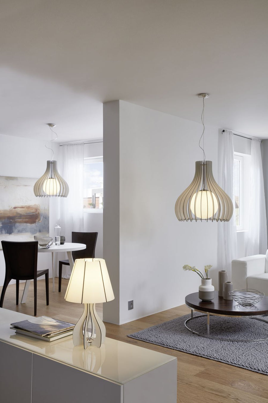Deux suspensions en situation près d'une table et d'un canapé, lumière chaude diffusée