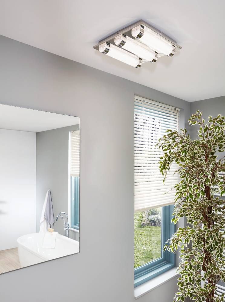Plafonnier allumé au plafond d'une salle de bain avec miroir et fenêtre