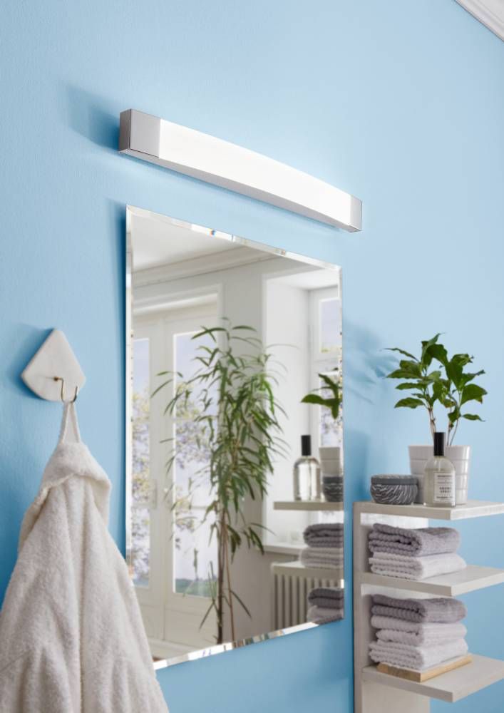 Applique allumée au-dessus d'un miroir dans une salle de bain bleue