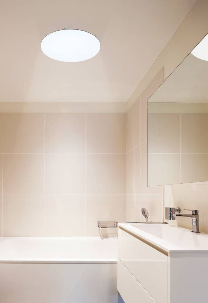 Mise en ambiance dans une salle de bains, plafonnier allumé au-dessus du lavabo