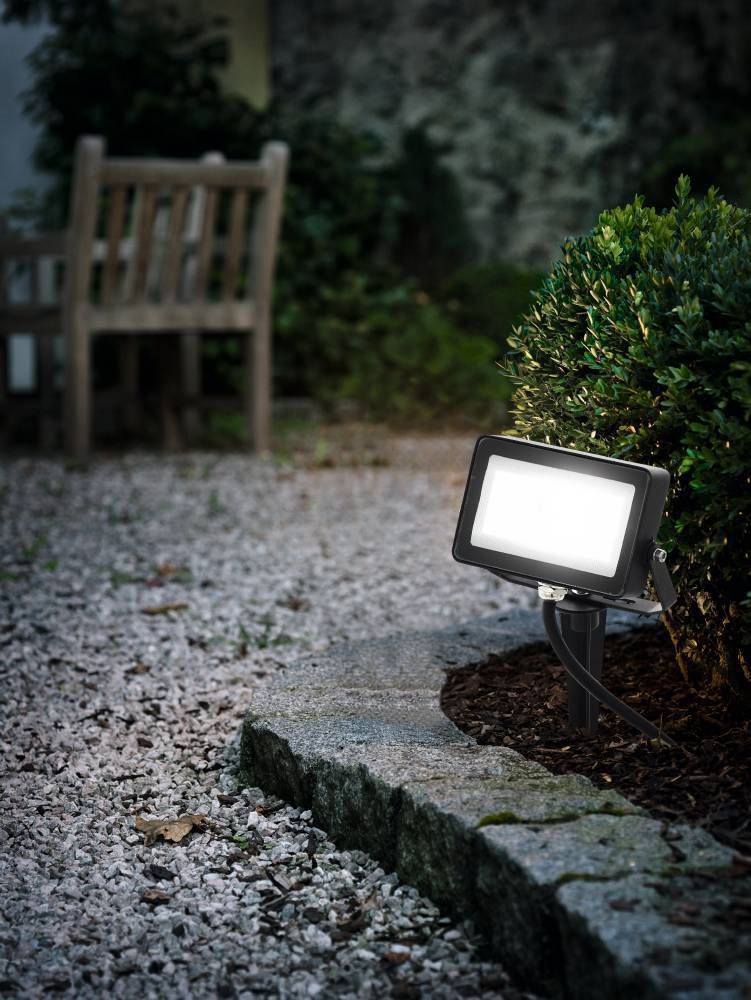 Mise en ambiance nocturne, projecteur allumé sur graviers près d'un buisson