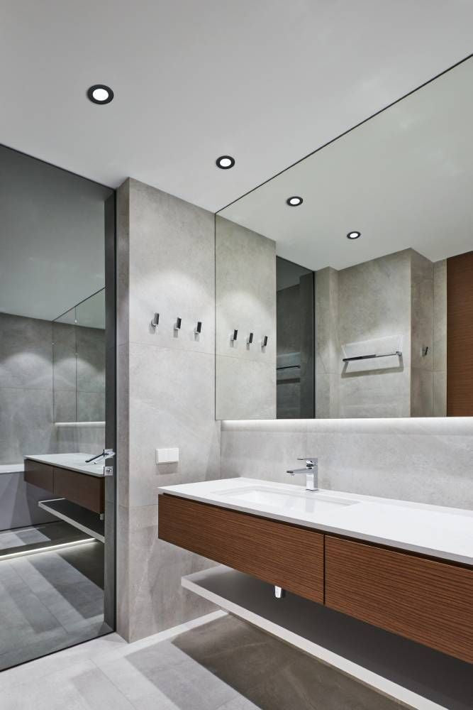 Spots encastrés au plafond éclairant une salle de bain moderne avec meuble vasque en bois.