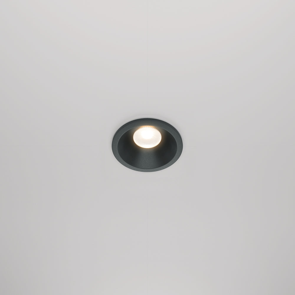Spot encastré rond noir monté seul au plafond blanc, vue de face