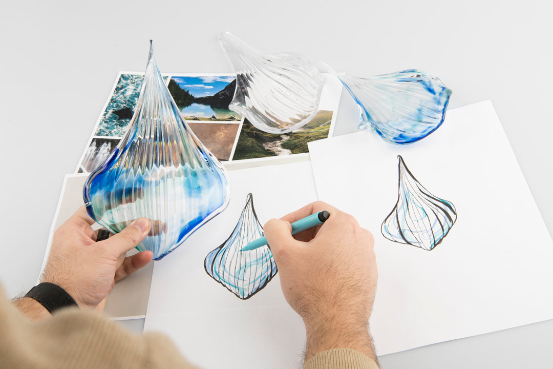 Mains tenant une pièce de verre strié devant des croquis et photos d'inspiration.