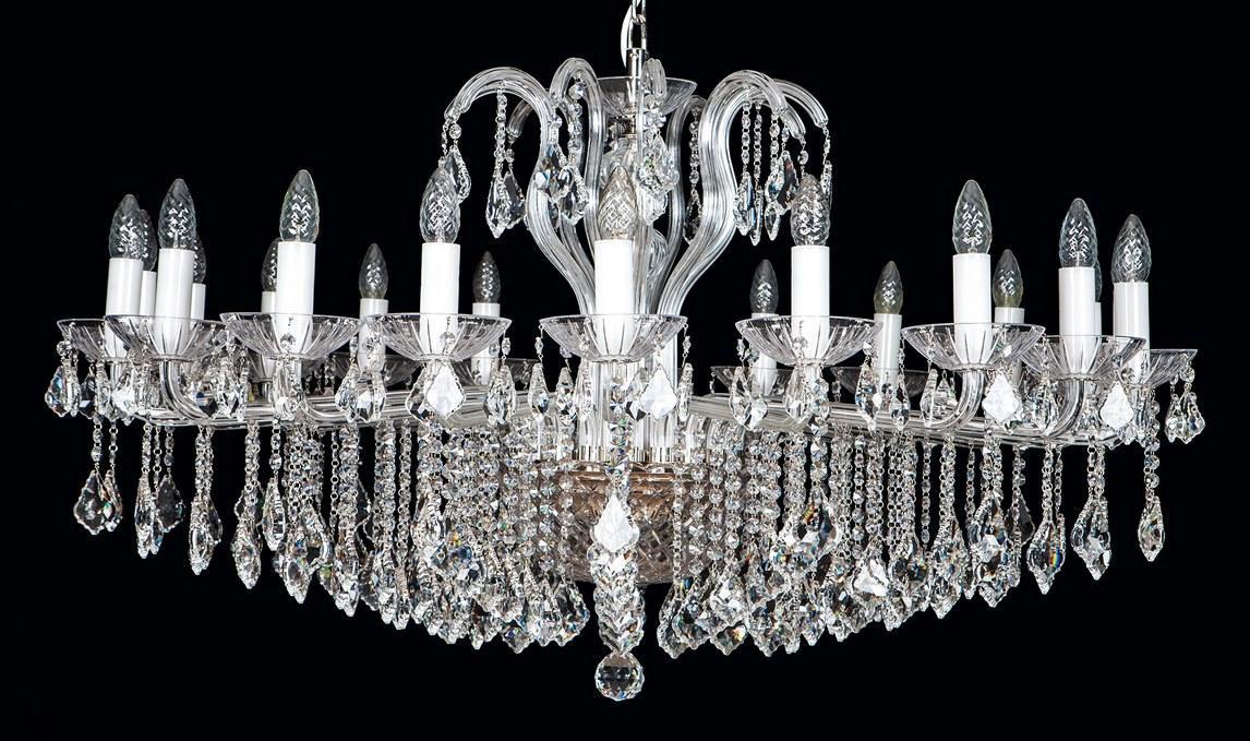 Lustre en cristal photographié de face sur fond noir, douze bras lumineux