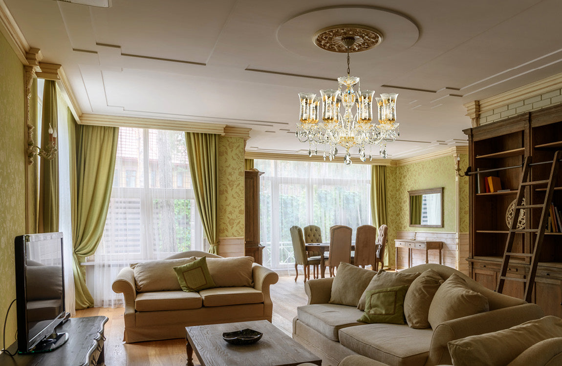 Lustre allumé suspendu dans un salon vert avec canapés beiges et fenêtres