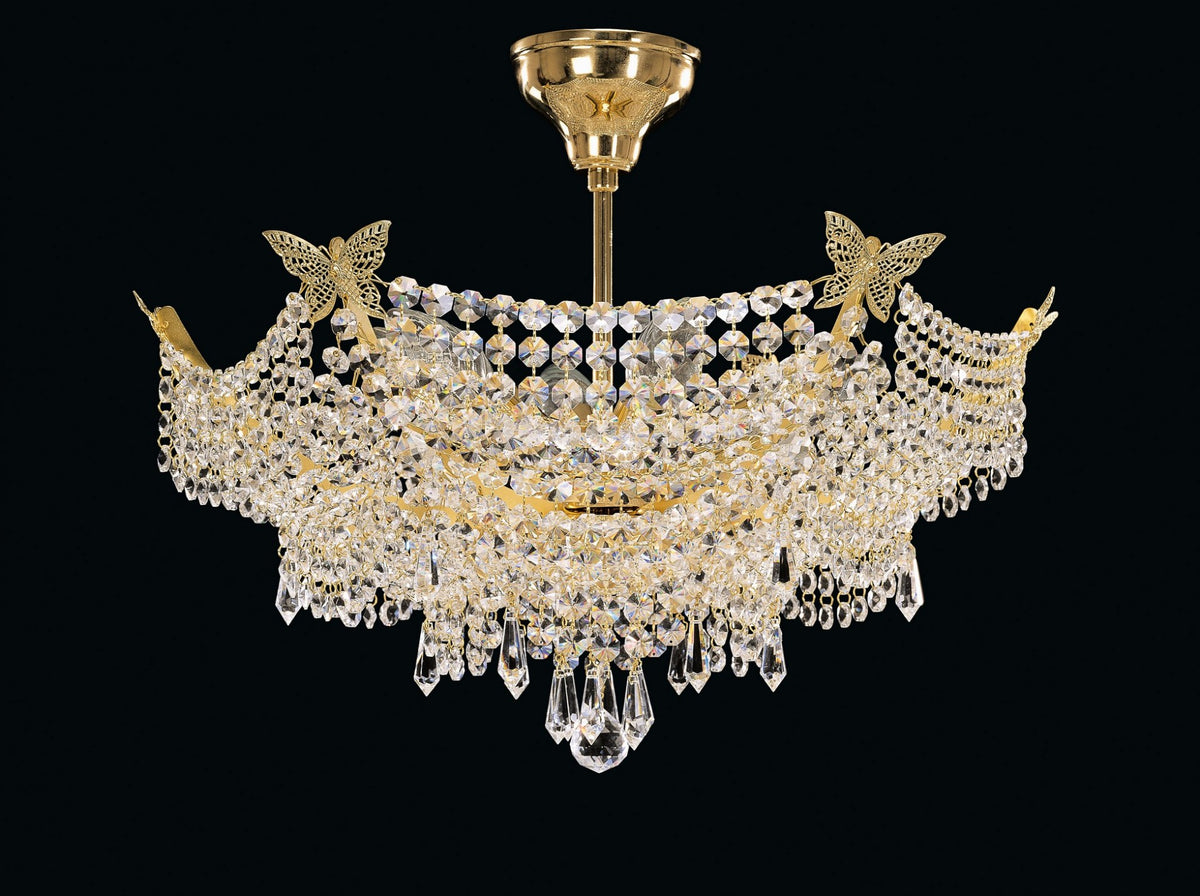 Lustre en cristal doré photographié de face sur fond noir, fixé au plafond