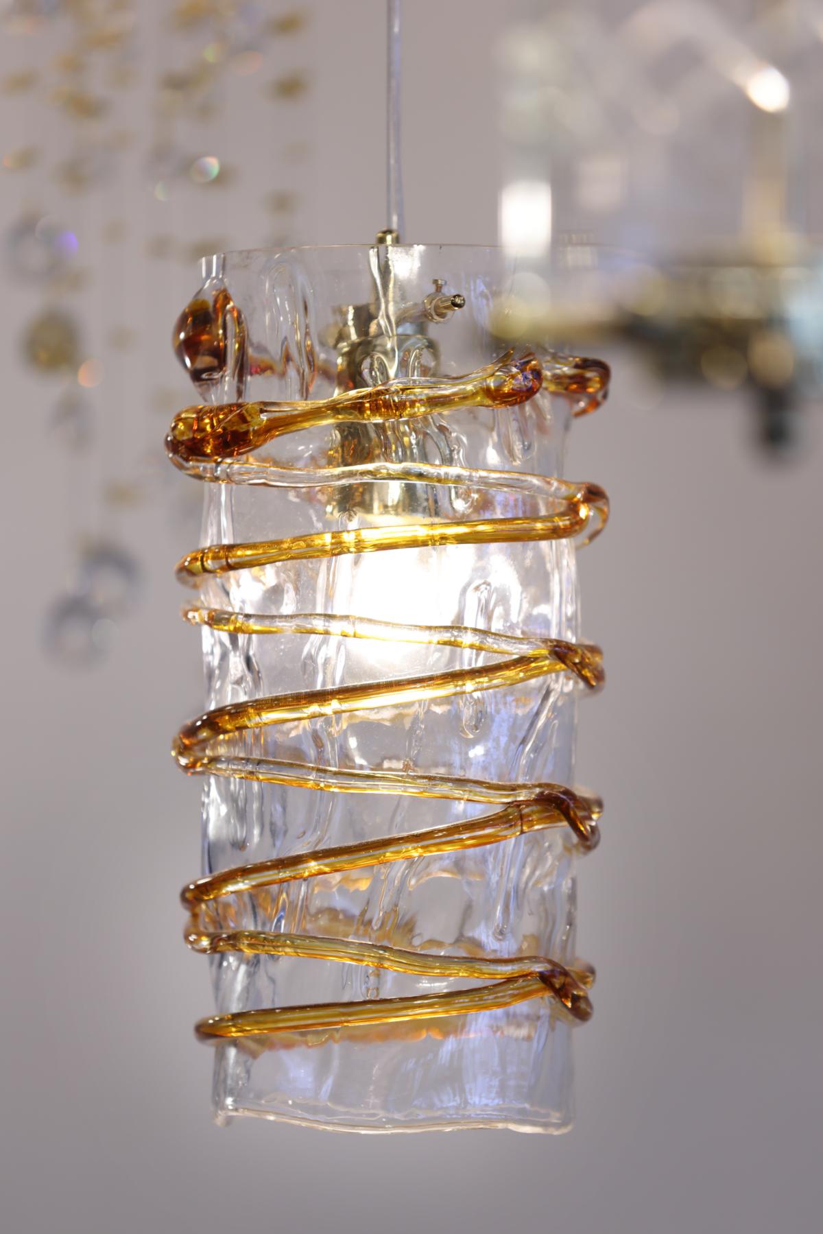 Détail rapproché de la spirale en verre ambré et du culot métallique sous la lumière allumée.