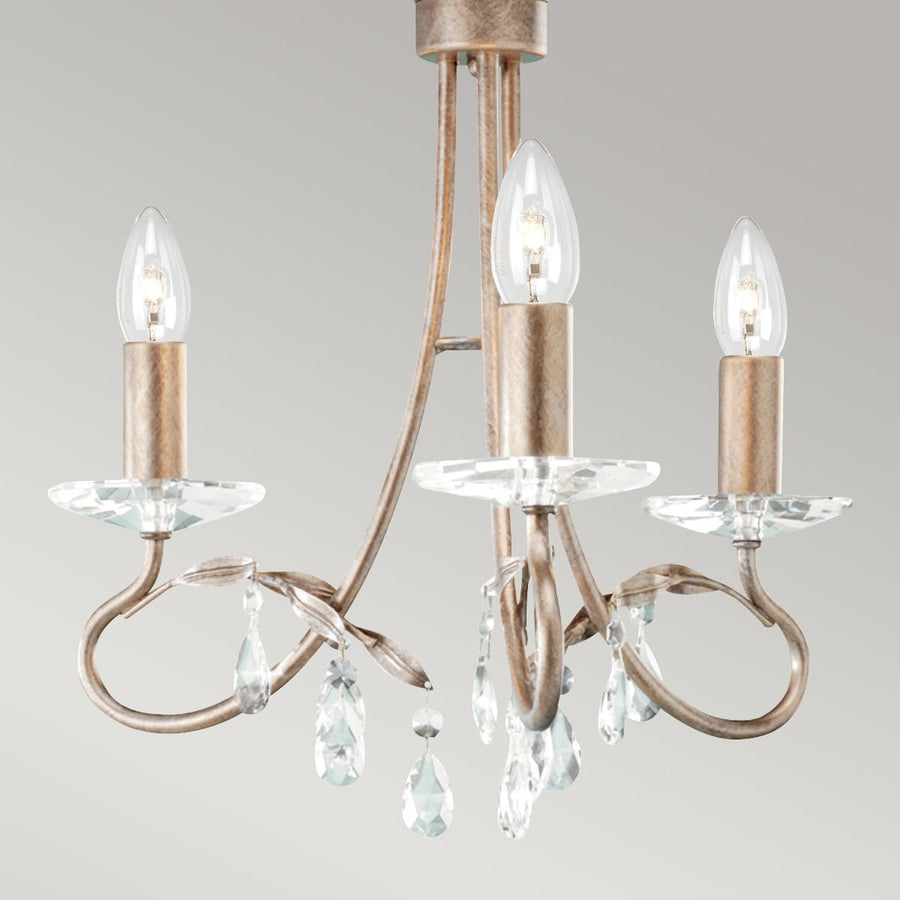 Gros plan sur les bras, coupelles et pampilles en cristal du luminaire.