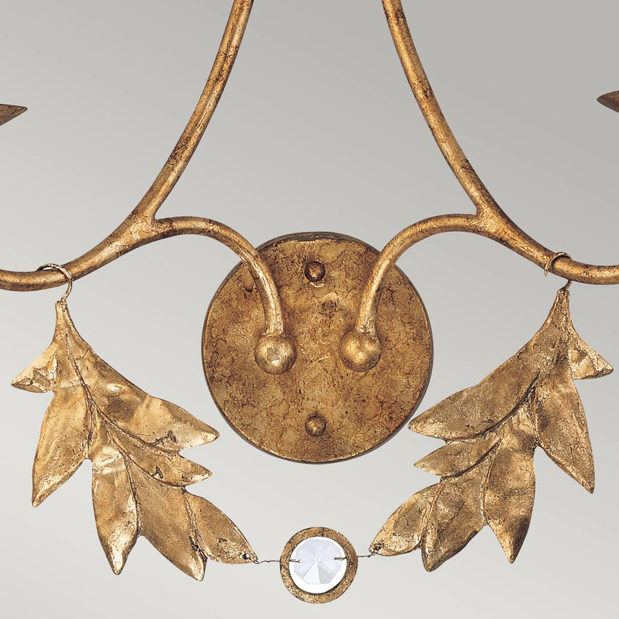Détail du centre : pastille ronde dorée, feuillage ajouré et cabochon de cristal