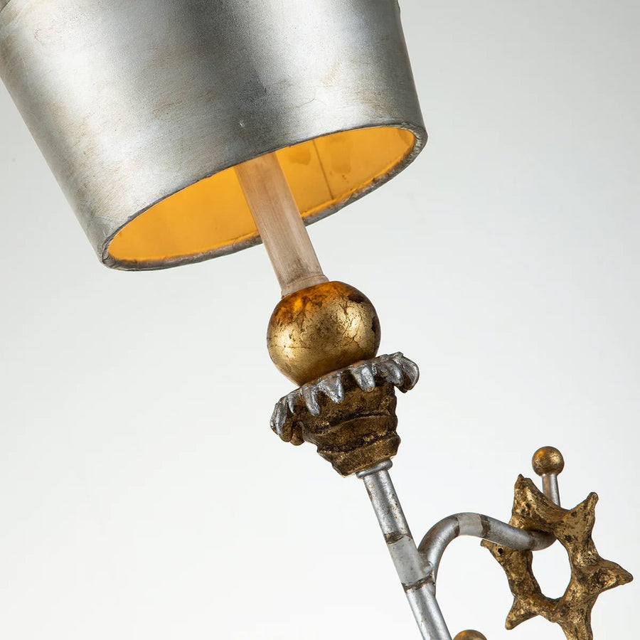 Détail rapproché de l'abat-jour argenté, tige et boule dorée, intérieur jaune.