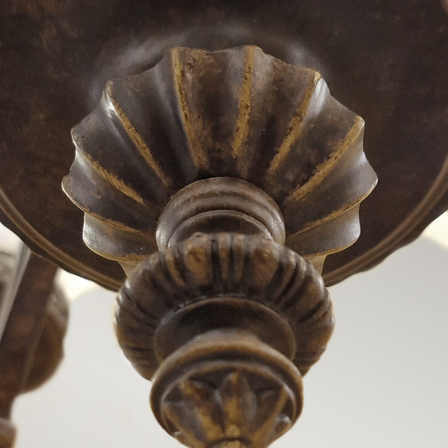 Détail du fleuron terminal sculpté à godrons dorés sous la base du lustre