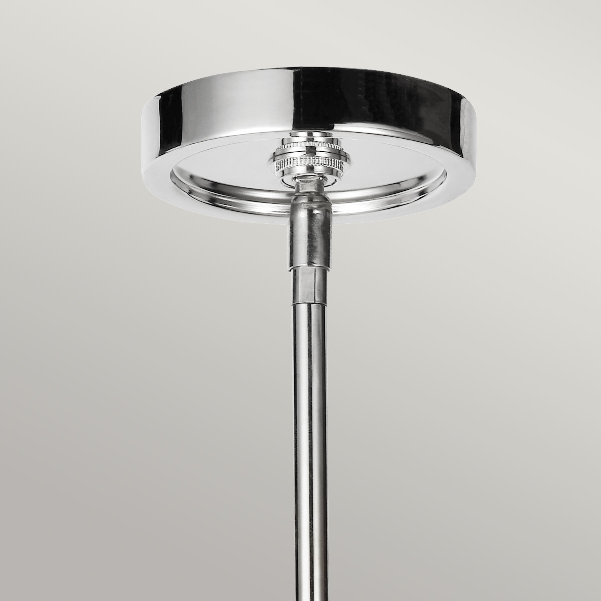 Détail de la rosace ronde en nickel poli fixée au plafond avec tige verticale